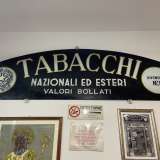 Il romano moderno � protagonista anche del logo pi� �recente� del Tabaccaio Di Monte, custodito all�interno del locale. La targa, in bianco e nero e risalente al 1943, presenta lo stile nella sua variante �raccordata�, ossia curva, quasi a voler imitare la forma di un semicerchio
